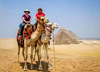 two-female-tourists-riding-camels-at-the-pyramids-of-giza-cairo-egypt